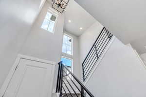 Staircase featuring a high ceiling, plenty of natural light, a chandelier, and recessed lighting