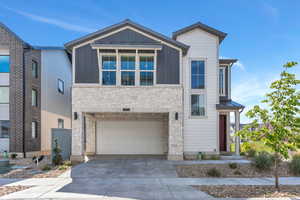 Contemporary home featuring stone, siding, driveway, and garage
