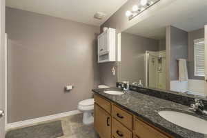 Full bathroom with a shower stall, double vanity, a garden tub, a textured ceiling, and granite countertops