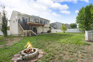 Back of house featuring stairway, a fenced backyard, a wooden deck, and an outdoor fire pit