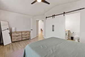 Bedroom featuring lofted ceiling, light wood finished floors, ensuite bathroom, a ceiling fan, and arched walkways