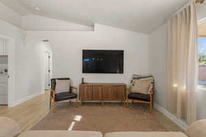 Sitting room with vaulted ceiling, arched walkways, and light wood-type flooring