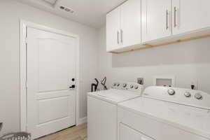 Washroom with independent washer and dryer and light wood-type flooring