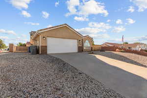 View of side of home with driveway, stucco siding, and an attached garage