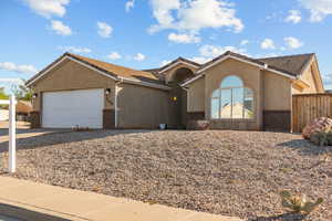 View of front of house featuring a tiled roof, an attached garage, stucco siding, and driveway