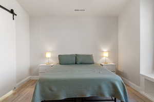 Bedroom featuring a barn door and light wood-style floors