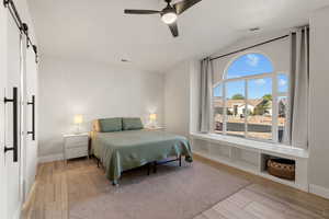 Bedroom with a barn door, wood tiled floors, lofted ceiling, and a ceiling fan
