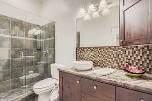 Bathroom featuring backsplash, vanity, and a stall shower
