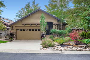 View of front of house with stucco siding, concrete driveway, an attached garage, and stone siding