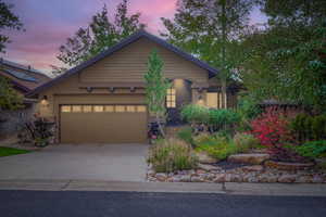 View of front facade featuring driveway, stucco siding, a garage, and stone siding