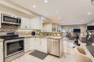 Kitchen featuring appliances with stainless steel finishes, backsplash, open floor plan, a peninsula, and recessed lighting