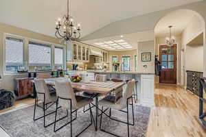 Dining area with a chandelier, vaulted ceiling, light wood finished floors, and recessed lighting