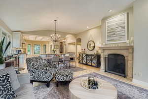 Living room with a premium fireplace, arched walkways, vaulted ceiling, a chandelier, and light wood-style floors