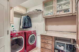 Washroom featuring cabinet space, separate washer and dryer, and light wood finished floors