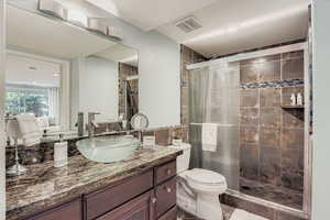 Bathroom with vanity, a shower stall, and dark tile patterned flooring