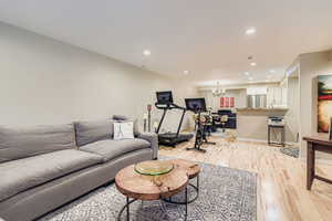 Living room with recessed lighting, light wood-style flooring, and a chandelier
