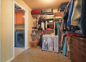 Walk in closet with light colored carpet and washing machine and clothes dryer