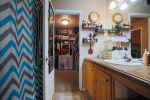 Full bath featuring a walk in closet, vanity, a shower with curtain, and light stone finish floors