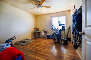 Workout area with dark wood-style floors and a ceiling fan