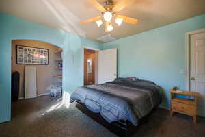Carpeted bedroom with a ceiling fan and baseboards