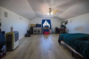 Bedroom with lofted ceiling, light wood-style flooring, and a ceiling fan