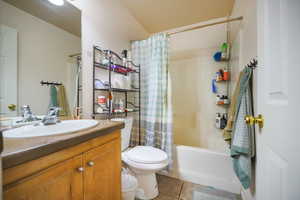 Bathroom featuring shower / bathtub combination with curtain, light tile patterned floors, and vanity