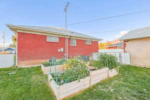 Rear view of property with brick siding, a shingled roof, and a vegetable garden