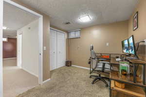 Home office featuring carpet and a textured ceiling