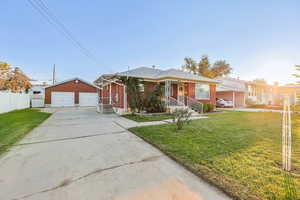 Bungalow-style house featuring brick siding, a garage, and an outbuilding
