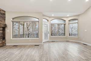 Unfurnished living room with light wood-style floors and recessed lighting.  Windows have remote operated blinds.