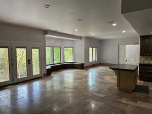 Basement kitchen featuring stone tile flooring, a kitchen island, open floor plan, recessed lighting