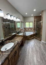 Bathroom featuring a bath, a shower stall, double vanity, and light wood-type flooring