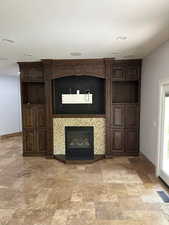 Basement living room featuring a fireplace and light stone finish floors