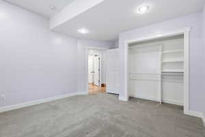 Unfurnished bedroom featuring light colored carpet, a closet, and recessed lighting