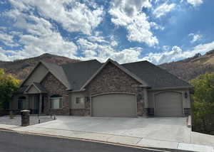 Craftsman-style house with a mountain view, concrete driveway, a garage, and stone siding