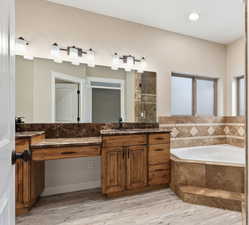 Primary bathroom with vanity, a garden tub, a stall shower, and light wood-type flooring