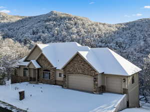 View of front of house featuring stucco siding, a garage, stone siding, and a mountain view