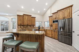 Kitchen featuring brown cabinetry, stainless steel appliances, decorative backsplash, light wood-style floors, and recessed lighting