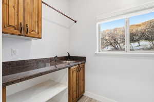 Laundry room featuring brown cabinets, dark stone counters, and light wood finished floors
