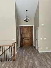 Entryway with high vaulted ceiling, LVP finished floors, a chandelier, and arched walkways