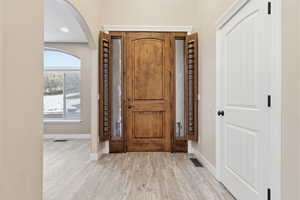 Foyer entrance with arched walkways and wood finished floors