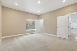 Guest bedroom with light colored carpet and recessed lighting