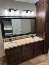 Basement bathroom featuring double vanity and stone tile flooring
