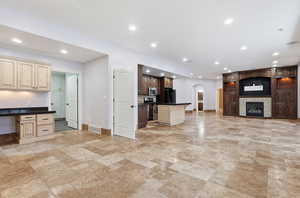 Unfurnished living room with arched walkways, built in desk, a fireplace, recessed lighting, and stone tile floors.  Perfect for multi gen living or rental