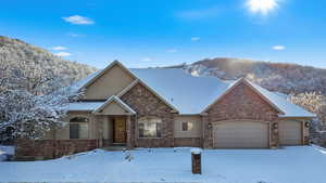 View of front of home featuring an attached garage, stucco siding, and stone siding