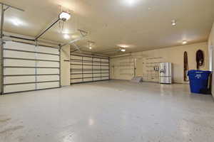 Three car garage with an extra refrigerator and a garage door opener