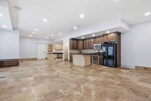 Second kitchen on a lower level featuring a kitchen bar, dark countertops,  appliances, a center island, and recessed lighting