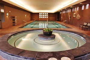 Indoor community pool featuring a hot tub