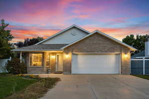 Single story home featuring brick siding, concrete driveway, a garage, and covered porch