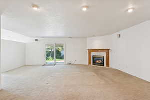 Unfurnished living room featuring a fireplace, a textured ceiling, and carpet floors